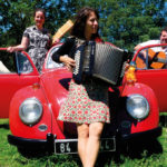 Le trio HerMaNa en photo à la sortie d'une vieille voiture